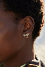 Load image into Gallery viewer, Gold dragonfly shaped earring hand-painted in green enamel and blue sapphires as eyes on model