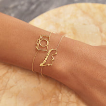 Load image into Gallery viewer, Gold chain bracelets with dinosaur and camera shaped pendant with small diamond worn by model