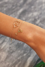 Load image into Gallery viewer, Gold chain bracelet with martini drink shaped pendant and small emerald worn by woman
